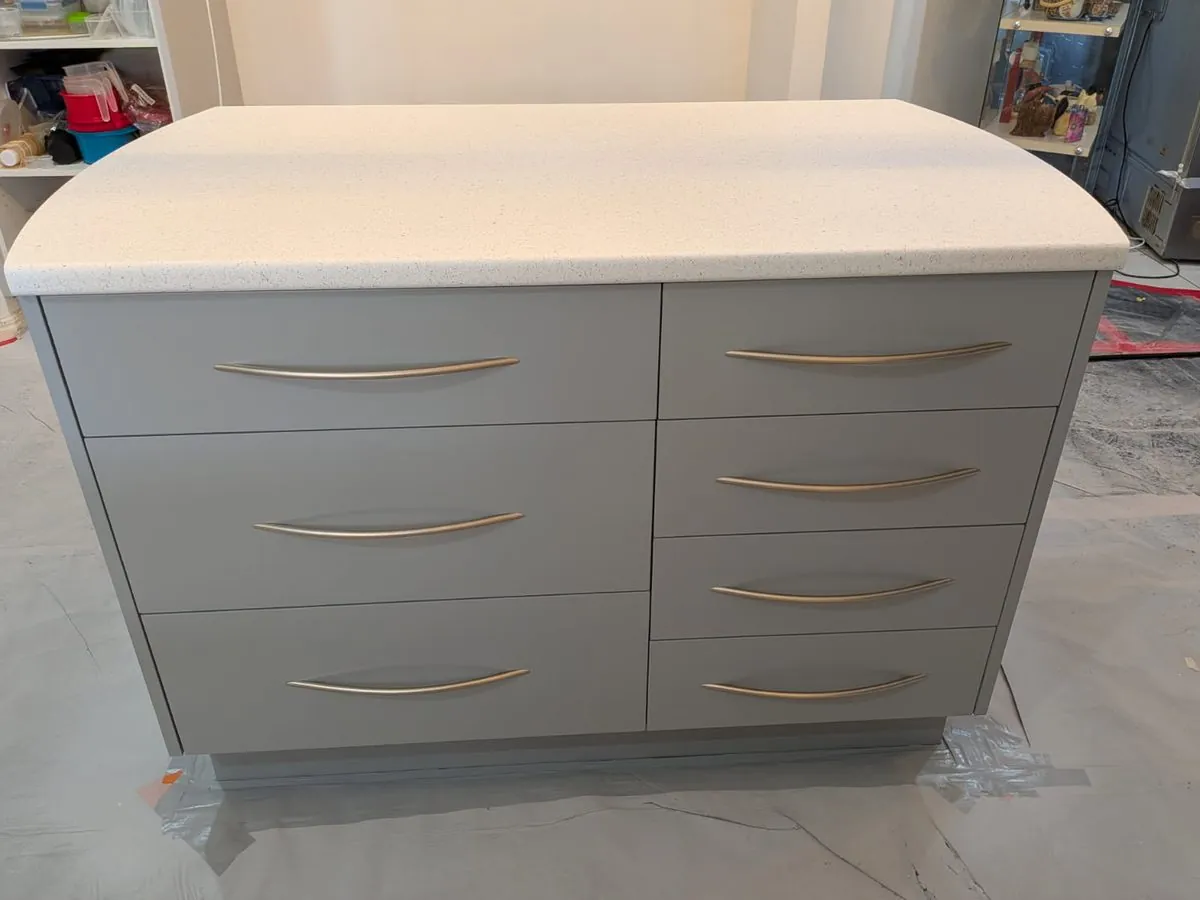 The same kitchen island after resurfacing, with grey drawers and a white stone-look benchtop